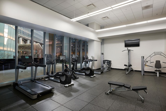 exercise room with a paneled ceiling and baseboards