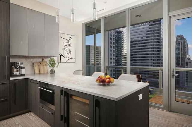 kitchen featuring tasteful backsplash, light countertops, light wood-style floors, modern cabinets, and a peninsula