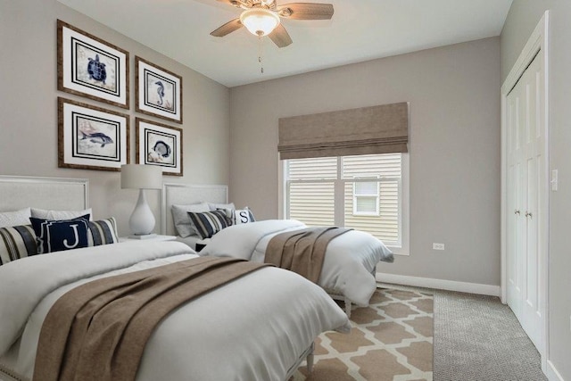 bedroom with a closet, light colored carpet, ceiling fan, and baseboards