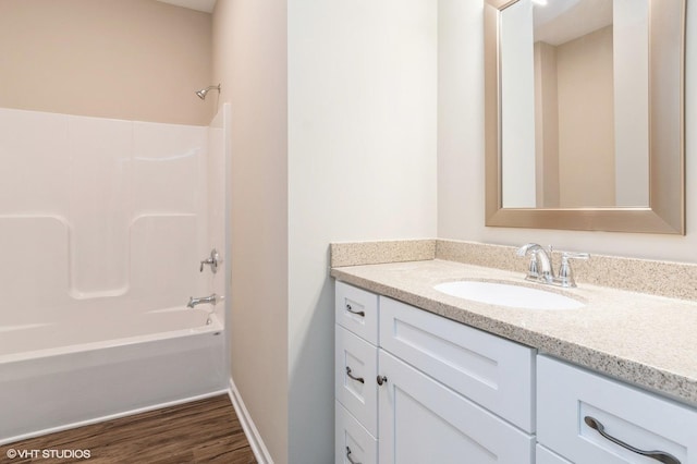 bathroom with washtub / shower combination, vanity, baseboards, and wood finished floors
