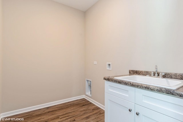 washroom with dark wood finished floors, hookup for a washing machine, cabinet space, a sink, and baseboards