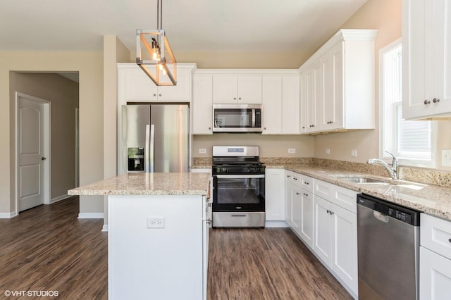 kitchen featuring dark wood-type flooring, a kitchen island, a sink, white cabinets, and appliances with stainless steel finishes