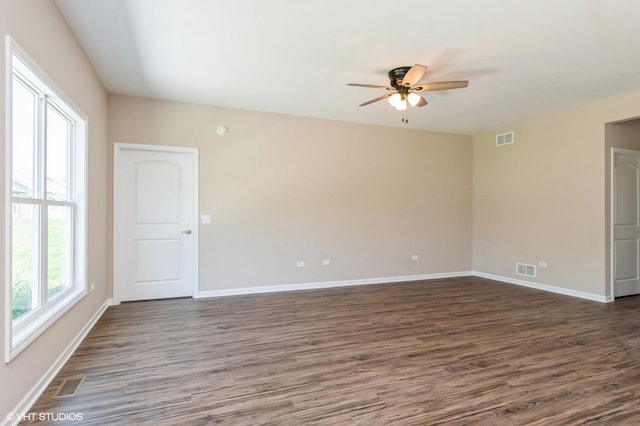 empty room featuring visible vents, dark wood finished floors, and baseboards