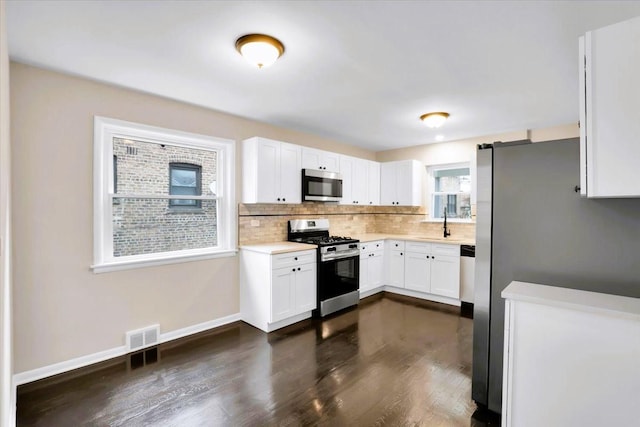 kitchen featuring stainless steel appliances, white cabinetry, baseboards, light countertops, and decorative backsplash