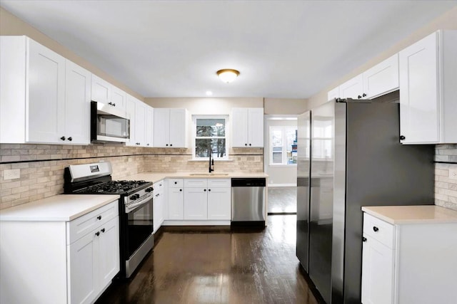 kitchen with stainless steel appliances, light countertops, a sink, and decorative backsplash