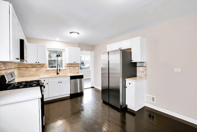 kitchen featuring dark wood-style flooring, visible vents, appliances with stainless steel finishes, a sink, and baseboards