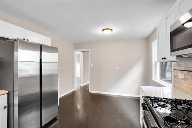 kitchen featuring white cabinets, appliances with stainless steel finishes, dark wood-style flooring, light countertops, and backsplash