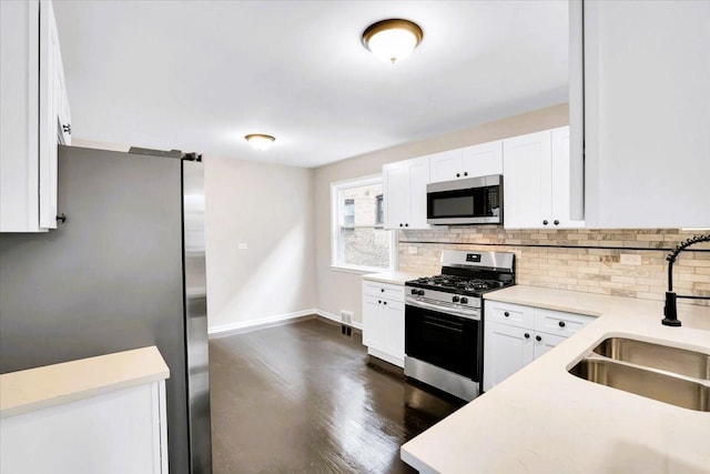 kitchen featuring tasteful backsplash, appliances with stainless steel finishes, light countertops, and a sink