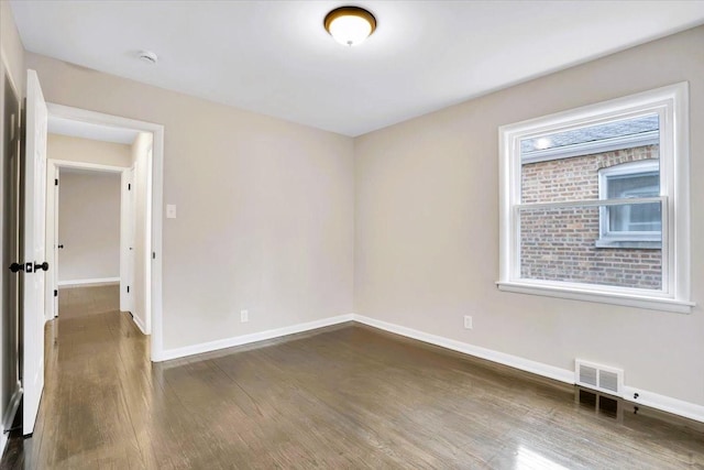 unfurnished room with baseboards, visible vents, and dark wood-type flooring