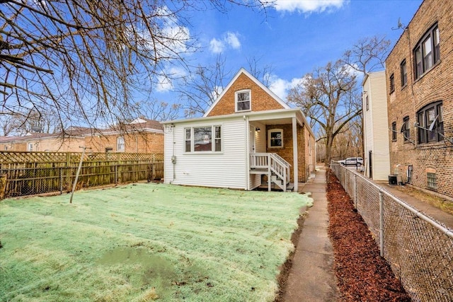 rear view of house featuring a yard, brick siding, central AC, and fence private yard