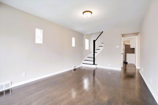 interior space with stairway, dark wood finished floors, visible vents, and baseboards