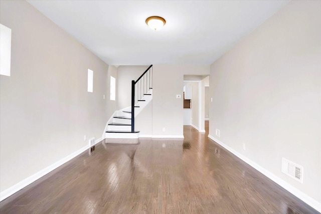 spare room featuring stairway, baseboards, visible vents, and wood finished floors