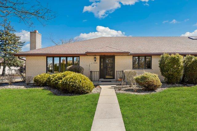 ranch-style house featuring brick siding, a chimney, and a front yard