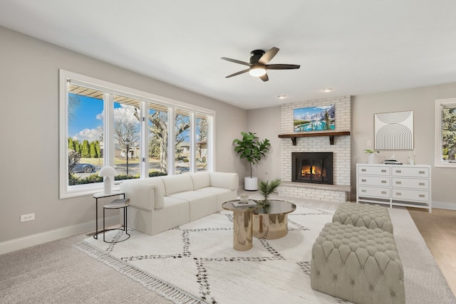 living area with ceiling fan, a fireplace, and baseboards