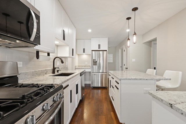 kitchen featuring pendant lighting, a sink, backsplash, dark wood-style floors, and appliances with stainless steel finishes