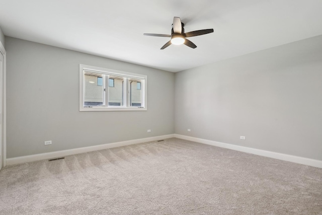 carpeted empty room featuring visible vents, ceiling fan, and baseboards