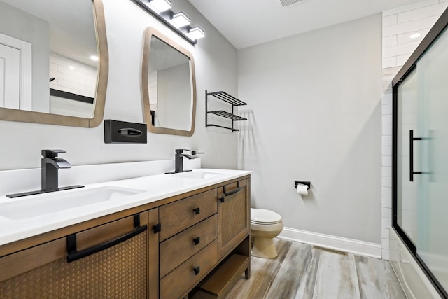 full bathroom with wood finished floors, toilet, baseboards, and a sink