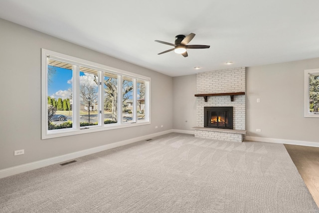 unfurnished living room featuring a ceiling fan, visible vents, a fireplace, and baseboards