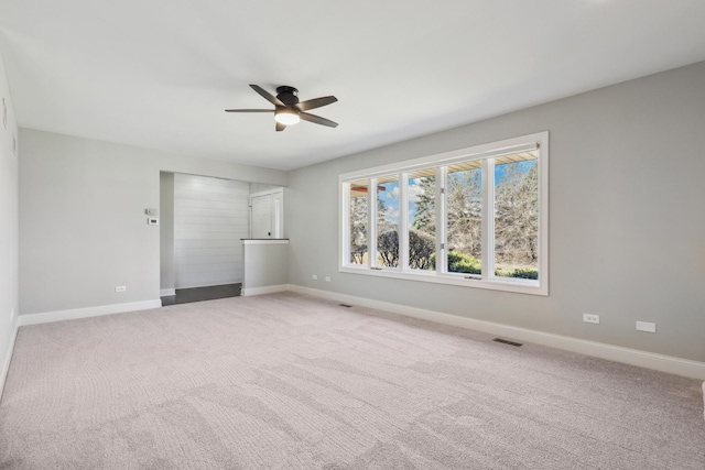 empty room with ceiling fan, baseboards, visible vents, and light carpet