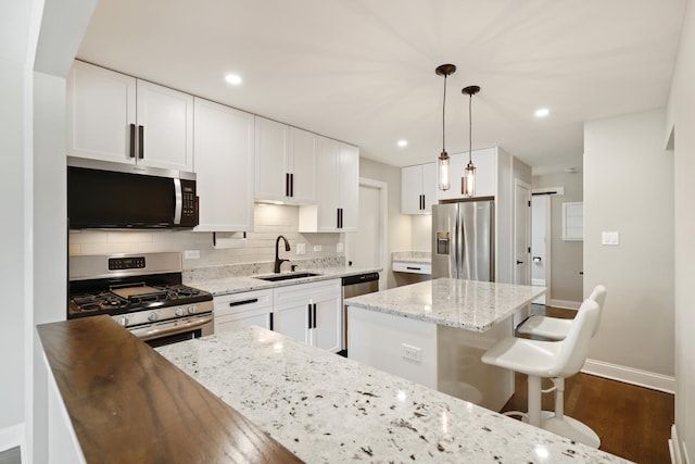 kitchen featuring a sink, decorative backsplash, dark wood-type flooring, appliances with stainless steel finishes, and white cabinetry