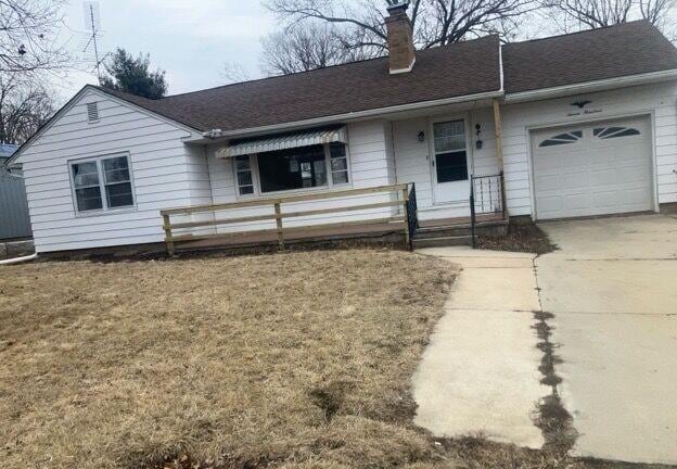 ranch-style house with a garage, concrete driveway, a shingled roof, and a chimney