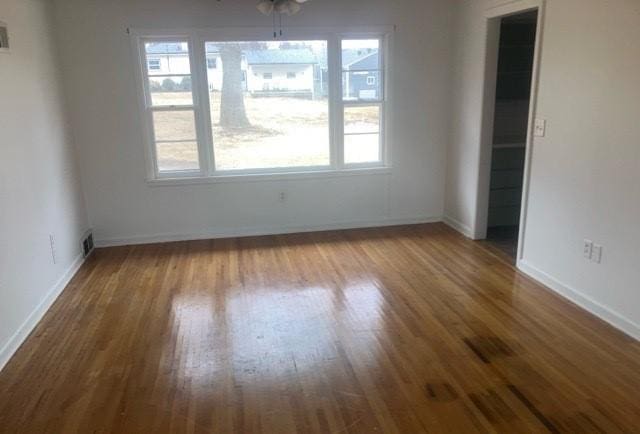 unfurnished dining area with wood finished floors, visible vents, and baseboards