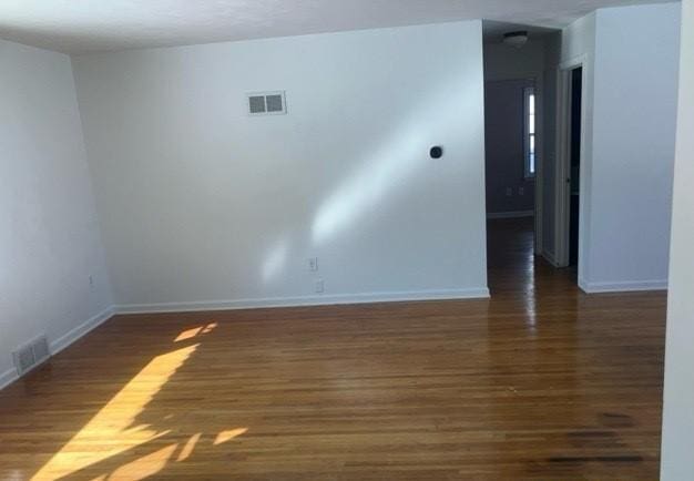 unfurnished room with baseboards, visible vents, and wood finished floors