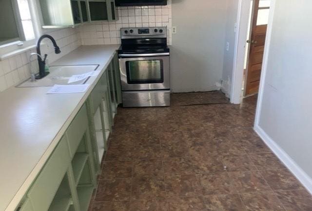 kitchen with a sink, green cabinets, light countertops, stainless steel electric range oven, and tasteful backsplash