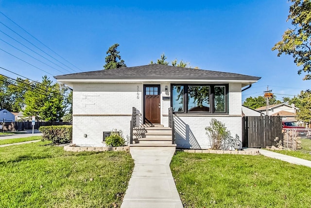 view of front facade with entry steps, a front yard, fence, and brick siding