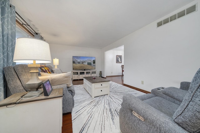 living room with baseboards, visible vents, and wood finished floors