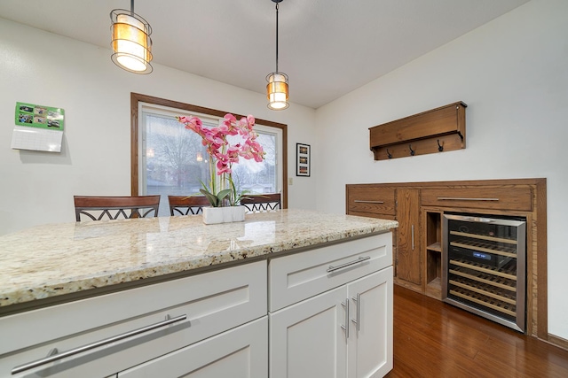 kitchen with wine cooler, dark wood-style flooring, white cabinetry, light stone countertops, and pendant lighting