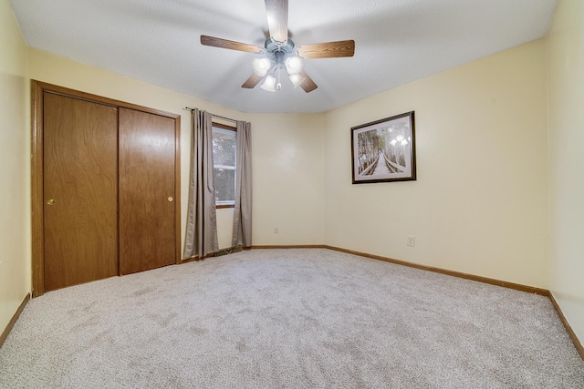 unfurnished bedroom with ceiling fan, a closet, carpet, and baseboards