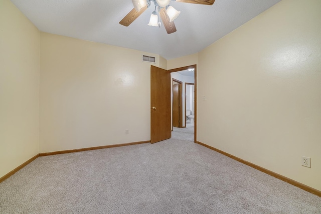 spare room featuring a ceiling fan, visible vents, light carpet, and baseboards