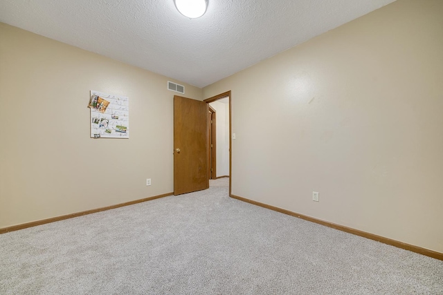 unfurnished room featuring light colored carpet, visible vents, a textured ceiling, and baseboards