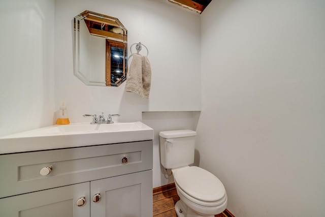 bathroom with vanity, wood finished floors, toilet, and baseboards