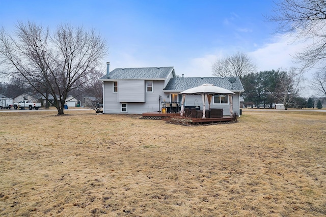 back of property featuring roof with shingles, a deck, and a gazebo