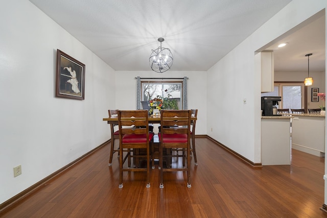 dining area featuring dark wood-style flooring, an inviting chandelier, and baseboards