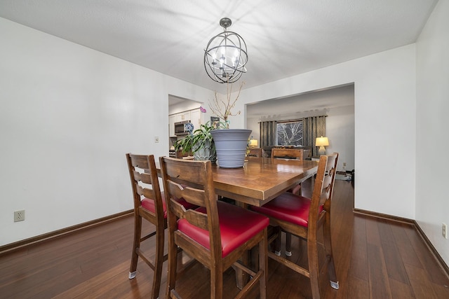 dining room with an inviting chandelier, wood-type flooring, and baseboards