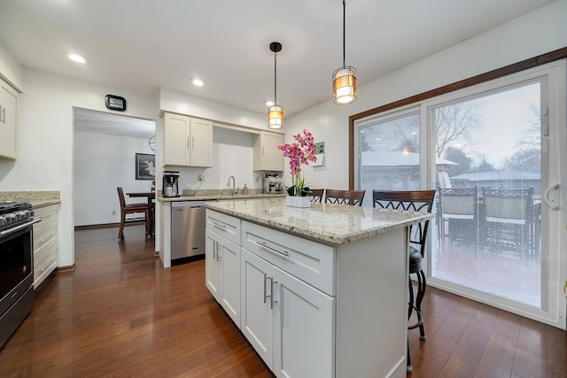 kitchen with a breakfast bar area, appliances with stainless steel finishes, dark wood-type flooring, white cabinetry, and a sink