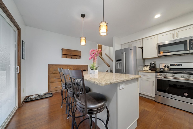 kitchen with white cabinets, a kitchen island, stainless steel appliances, and dark wood finished floors