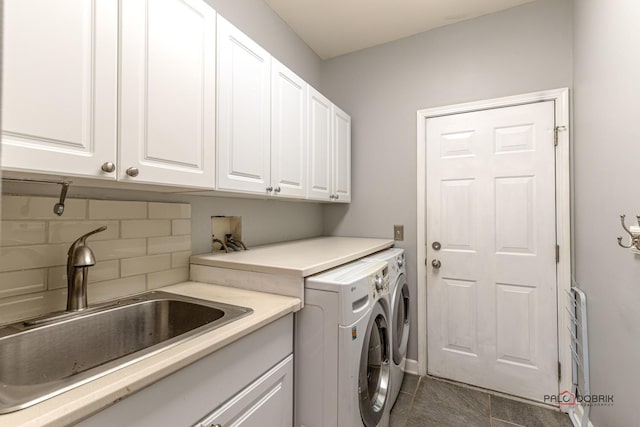 washroom with cabinet space, dark tile patterned flooring, washer and clothes dryer, and a sink