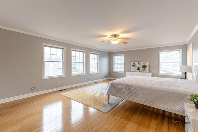 bedroom with light wood finished floors, visible vents, baseboards, and crown molding