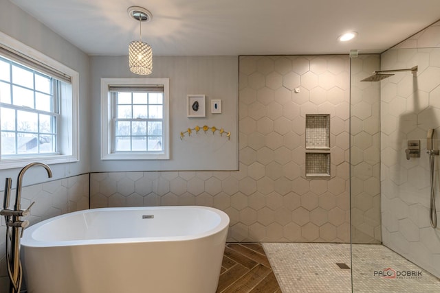 bathroom featuring tile walls, a freestanding bath, and walk in shower