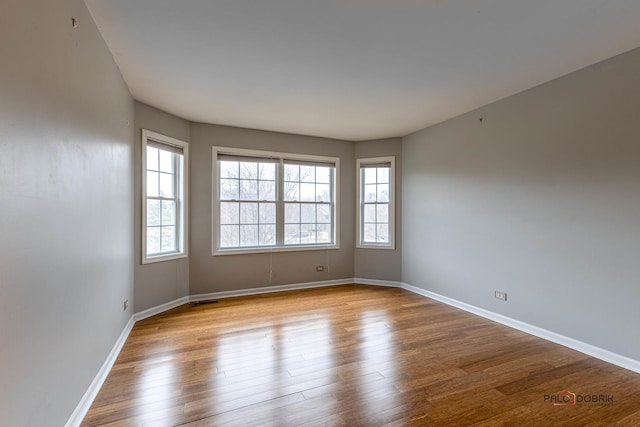 spare room with visible vents, baseboards, and wood finished floors