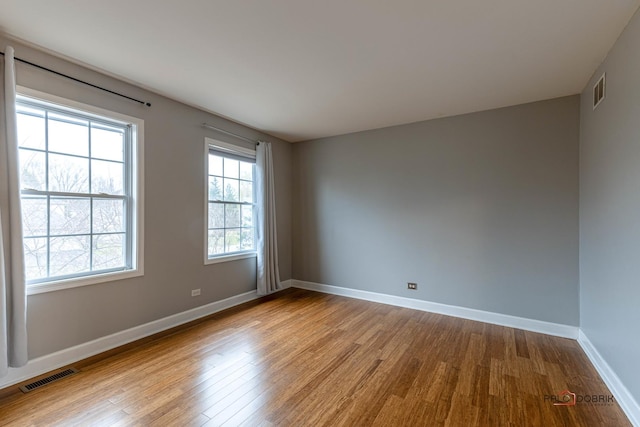 spare room featuring visible vents, baseboards, and wood finished floors