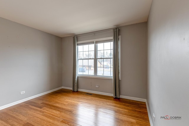empty room featuring visible vents, baseboards, and light wood finished floors