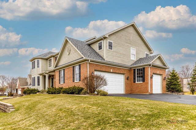 view of side of property featuring a lawn, aphalt driveway, roof with shingles, and brick siding