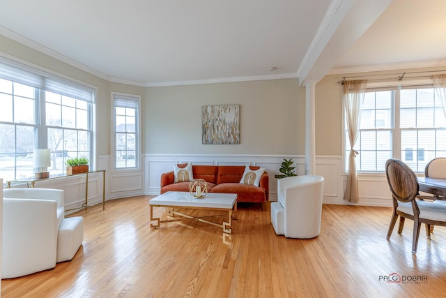 living room with wainscoting, wood finished floors, decorative columns, and ornamental molding