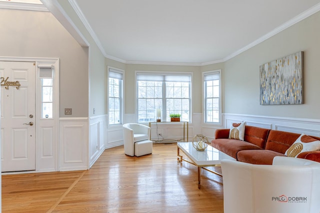 living room with light wood-style floors, crown molding, and wainscoting