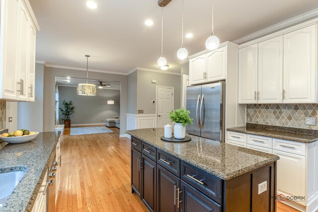 kitchen featuring white cabinetry, freestanding refrigerator, crown molding, and a ceiling fan